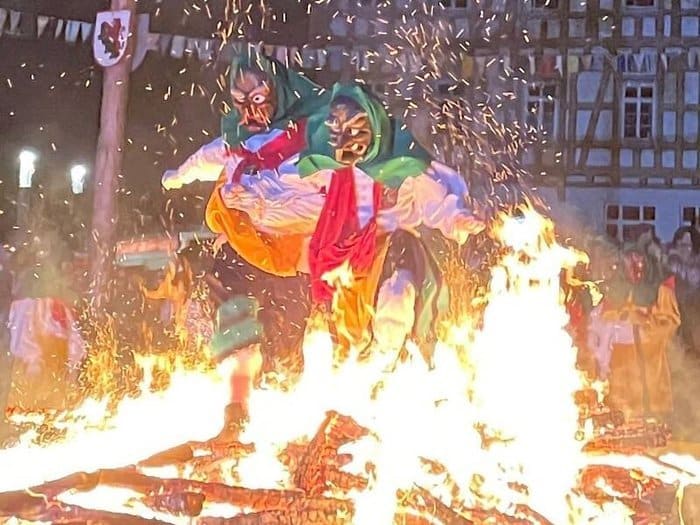 Maskierte Hexen springen über ein Feuer auf dem Schlossplatz