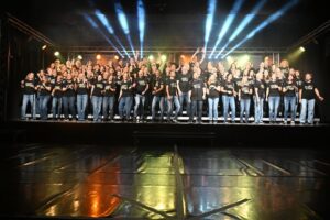 Der Chor Mix Dur in schwarzen „From Now On“-T-Shirts auf der beleuchteten Bühne