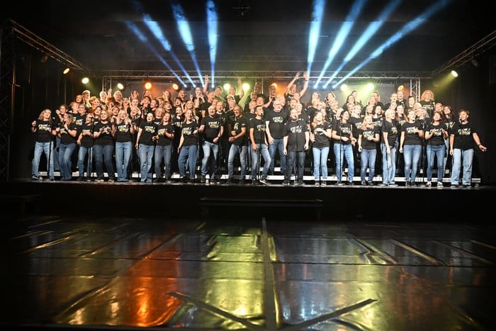 Der Chor Mix Dur in schwarzen „From Now On“-T-Shirts auf der beleuchteten Bühne
