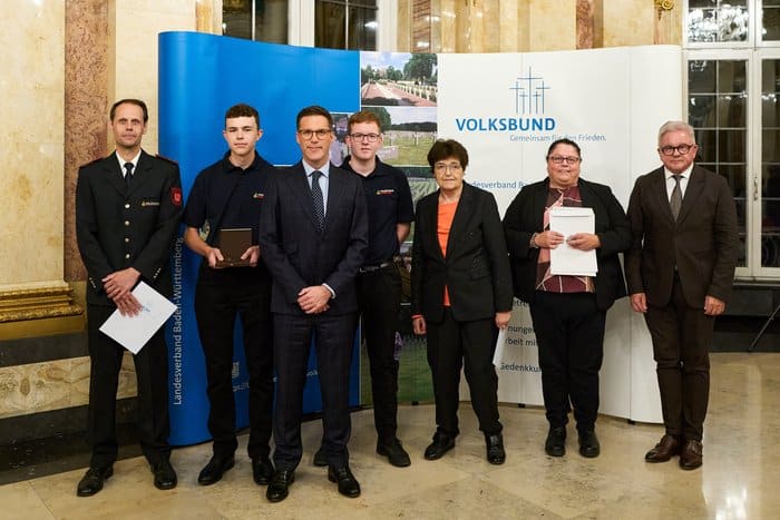 Gruppenfoto der Geehrten vor einer Volksbund-Stellwand im Neuen Schloss Stuttgart